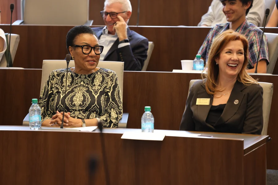 Attendees smile during a University Senate meeting in a lecture hall